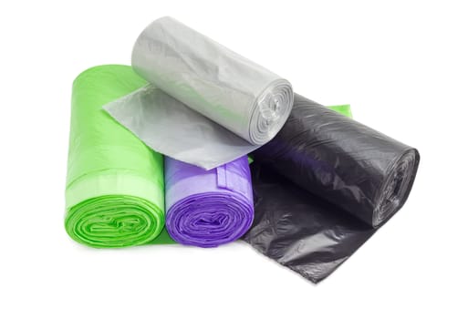 Several plastic disposable garbage bags of different sizes and colors in rolls including biodegradable on a light background
