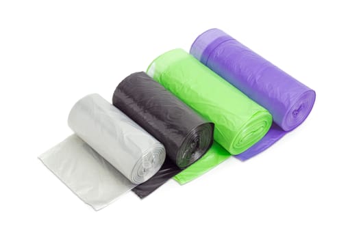 Several plastic disposable garbage bags of different sizes and colors in rolls including biodegradable and with handles, made from ribbon which may be tied on a light background
