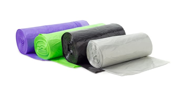 Several rolls of plastic disposable garbage bags of different sizes and colors including biodegradable on a light background
