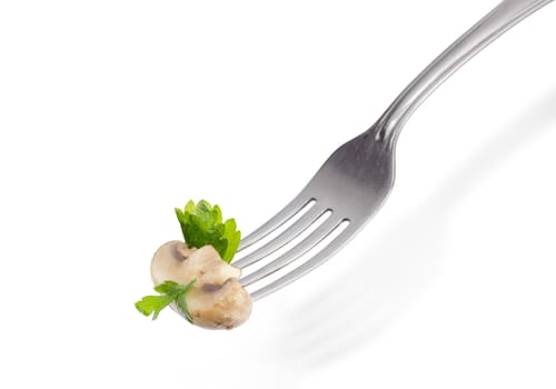 Half of the fried button mushroom with slices of a parsley leaves on the stainless steel fork closeup on a light background
