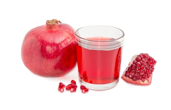 Pomegranate juice in a glass, one ripe whole pomegranate, part of the fresh split pomegranate and several pomegranate seeds on a light background

