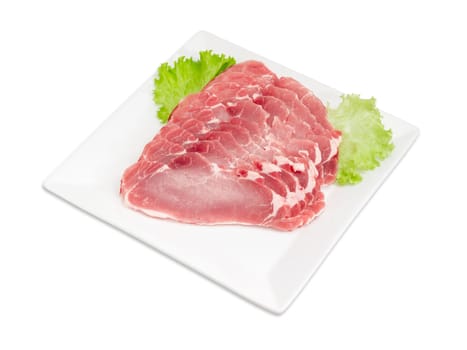 Sliced fresh chilled pork loin with lettuce leaves on a square white dish on a light background 
