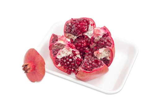 Split ripe fresh pomegranate on the plastic tray on a light background
