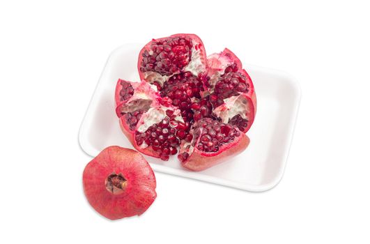 Split ripe fresh pomegranate on the plastic tray on a light background
