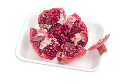 Split ripe fresh pomegranate on the plastic tray on a light background
