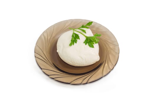 Piece of fresh mozzarella cheese with twig of parsley on the glass saucer on a light background
