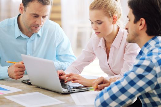 Team of people in casual clothes working with laptop together