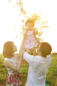 Portrait of lovely family enjoying outdoor activity together, walking on garden park in beautiful sunset during holiday vacations.