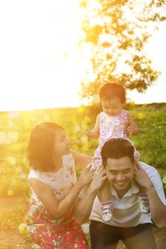 Portrait of happy family enjoying outdoor activity together, playing on garden park in beautiful sunset during holiday vacations.