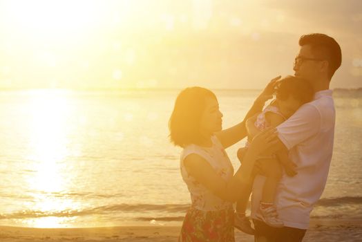 Silhouette of Asian family outdoor portrait, enjoying holiday together on seaside in beautiful sunset during vacations.