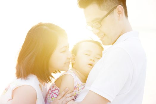 Lovely Asian family outdoor portrait, enjoying holiday together on seaside in beautiful sunset during vacations.