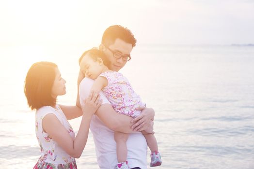 Asian family outdoor portrait, enjoying holiday together on coastline in sunset during vacations.