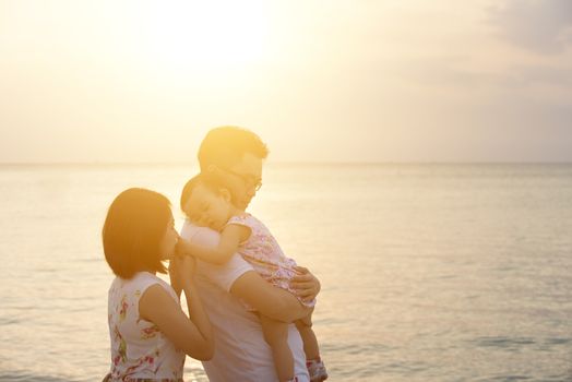 Asian family outdoor portrait, enjoying holiday together on seaside in sunset during vacations.