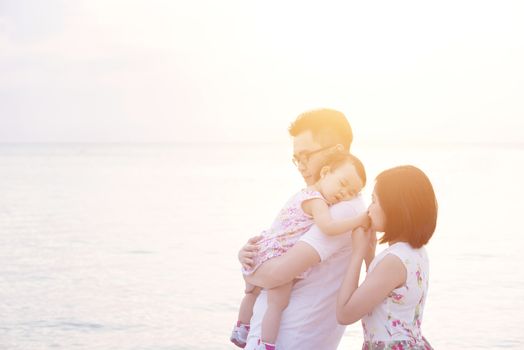 Asian family outdoor portrait, enjoying holiday together on beach side in sunset during vacations.
