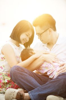 Asian family outdoor portrait, having fun time together on beach in sunset during vacations.