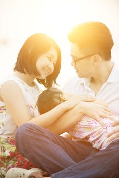 Happy Asian family outdoor portrait, having fun time together on beach in sunset during vacations.