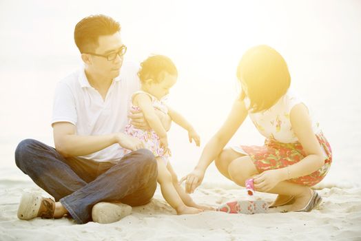 Happy Asian family outdoor activity, playing together on seaside in sunset during vacations.