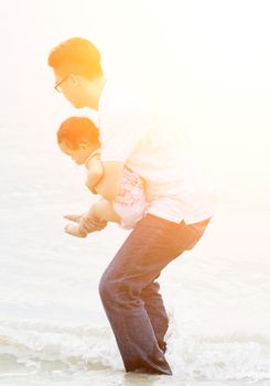 Family enjoying outdoor activity together, playing on beach in beautiful sunset during holiday vacations.