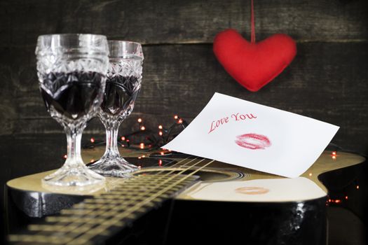 Happy Valentine's Day Kiss On White Paper With Text Love You On it, Resting on Acoustic Guitar With Vine Glasses, Lights and Heart