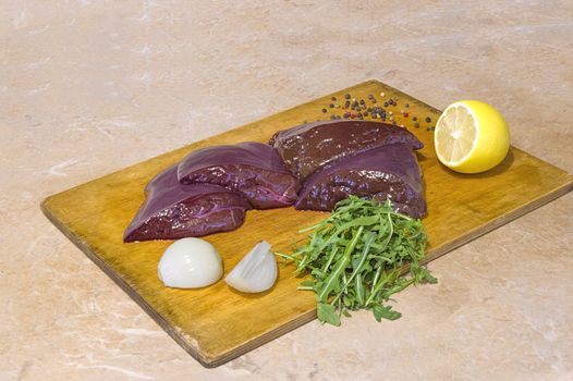 fresh veal liver with onions on a wooden cutting board