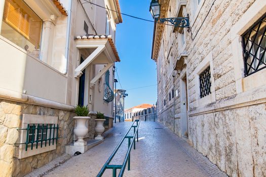 Passage way in a portuguese sidewalk between typical building in cascais during a bright sunny day.