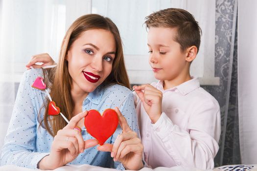 Happy Valentines Day or Mother day. Young boy and mum celebrate with gingerbread heart cookies on a stick.