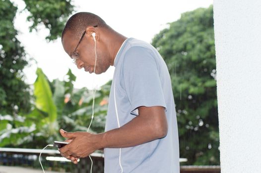 young man holding his mobile phone in hand and communicating with an earpiece.