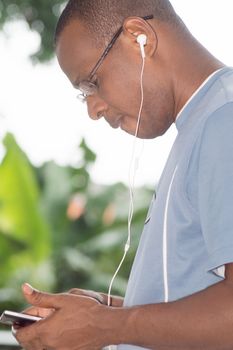 young man holding his mobile phone in hand and communicating with an earpiece.