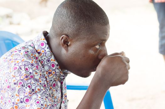 with a traditional cup in hand , this young man refreshes the throat by the palm wine.