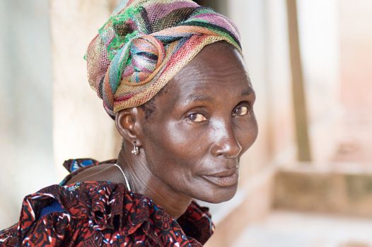 This woman is dressed the head tied with a head scarf and with a camisole.