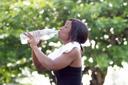 This young woman drinks mineral water after sport .