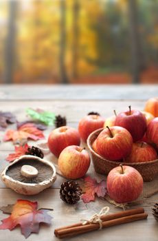 Leaves, apples over a wooden table in an autumn forest 