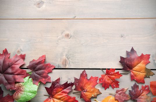 Autumn leaves on top of a wooden background with space