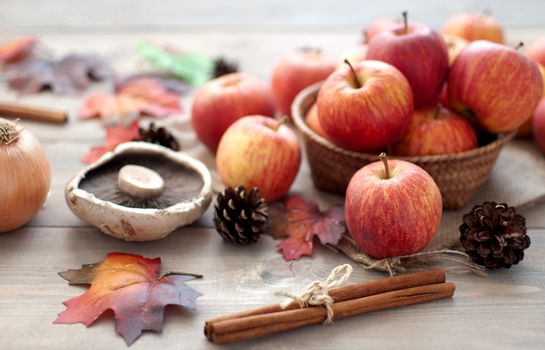 Autumn leaves with apples over a wooden background