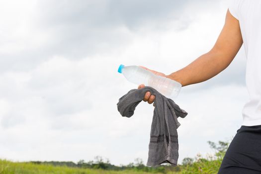 Man with water bottle and towel in his hand and nature background view.1