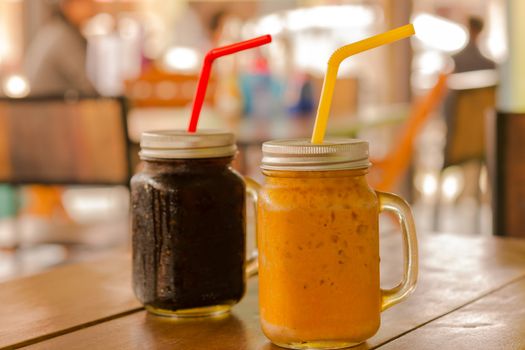 Ice tea and ice coffee in mason jars on table and background of restaurant in Asia.