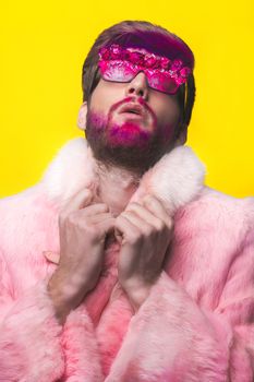 Portrait of glamour man with red beard. Guy in a pink fur coat and funny  sunglasses.