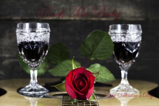 Red Rose and Wine Glasses Resting On Acoustic Guitar With Sign Rock Me Baby. Valentine's day concept