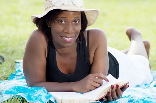 this young woman lying in the shade of a tree is reading quietly.