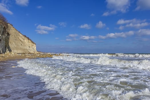 Beauty day view of rocky coast with waves and clouds