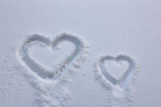 Big and small hearts drawn in the snow