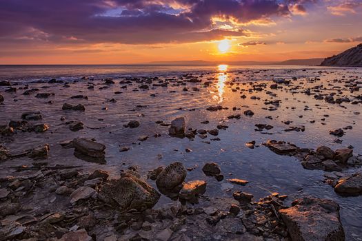 Exciting  rocky coast sunset with water reflection