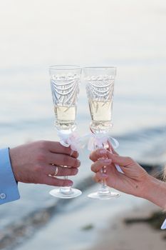 bride and groom with glasses of champagne in his hand against the sea
