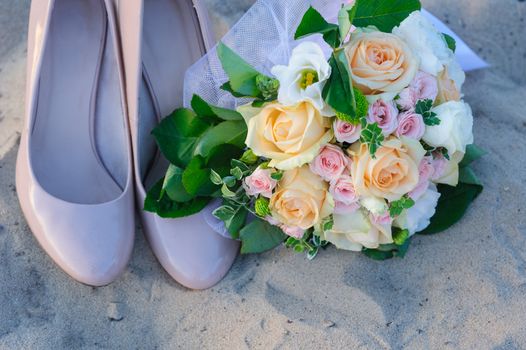 wedding bouquet and shoes in the sand.