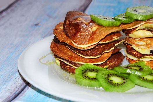 Delicious pancakes with kiwi on wooden table