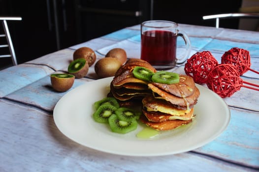 Delicious pancakes with kiwi on wooden table