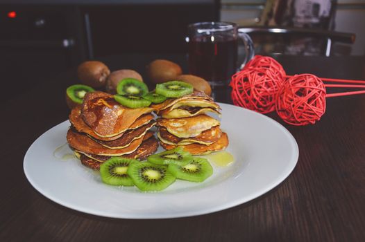Delicious pancakes with kiwi on wooden table