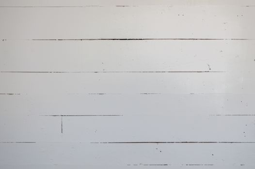 7 or 8 antique wooden boards run horizontally in an old farm house.  They are rustic and painted white.