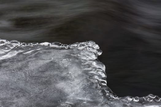 Icy ornaments on a small stream, black water