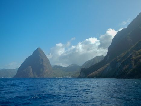 Petit and Gros Pitons and Sea in Petit and Gros Pitons and Sea in Saint Lucia from the south on a sunny day with blue sky and white puff clouds
